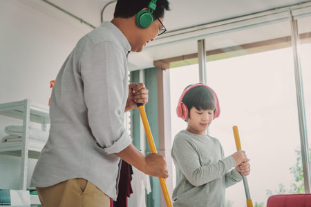 Father and son is wearing Music headphone while doing house cleaning with joy and happiness, for Family togetherness cocnept.の写真素材