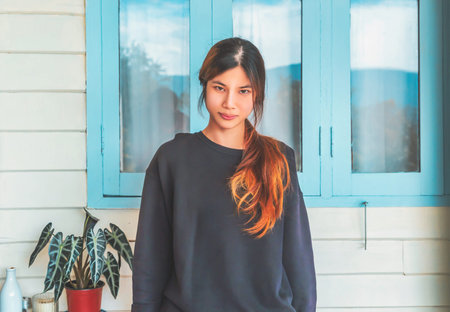 Asian woman standing infront of the pastel wooden house.