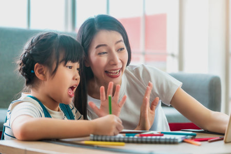 Asian Mother and Child saying hi to the teacher in online School Education at home. for New normal Online Education concept.の写真素材