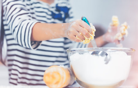 Child hand working together to mix flour and ingredient for Cooking and Baking bakery in home kitchen.の写真素材