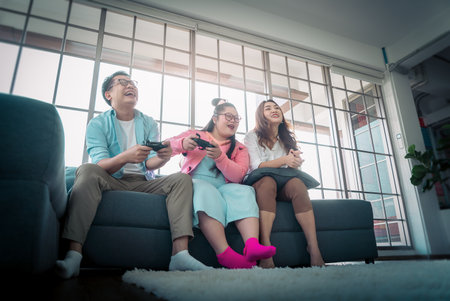 Asian Family with Down Syndrome daughter playing Video game together in living room at home for Autism positive family concept.の写真素材