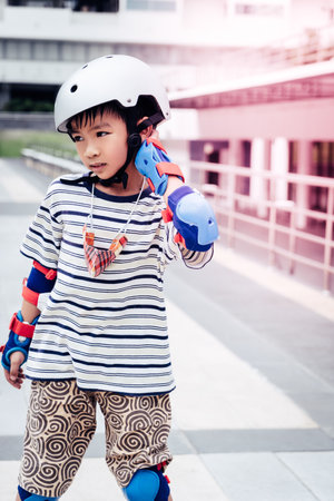 Little Asian Boy is learning to Skate on an Roller in park with full protection gear and helmet.の写真素材