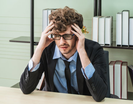 Depressed office worker business manger with frustrated expression on office desk feeling despair about business problem.の写真素材