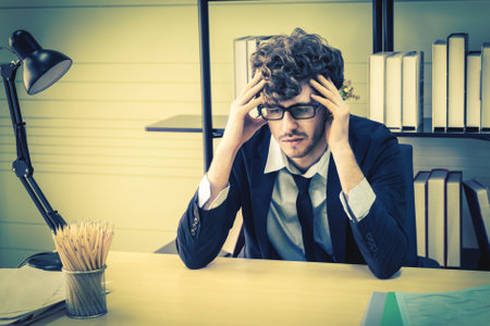 Depressed office worker business manger with frustrated expression on office desk feeling despair about business problem.の写真素材