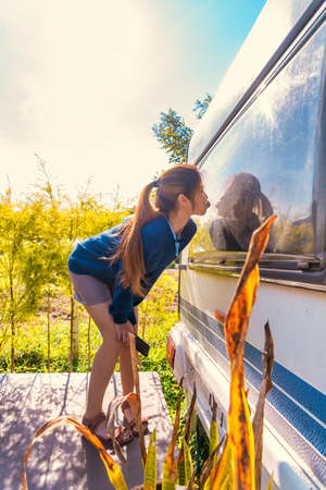 Female asian is standing beside the trailer home in Camping ground area.の写真素材