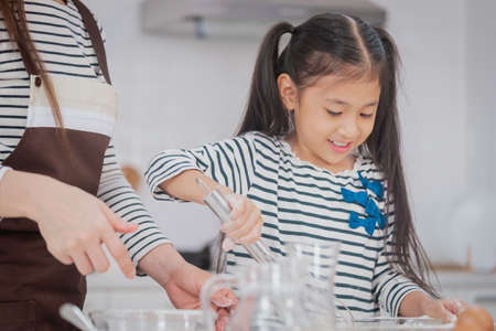 Mother and child working together to mix flour and ingredient for Cooking and Baking bakery in home kitchen.の写真素材
