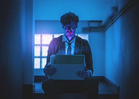 Depressed Umemployed Business office worker is sitting with card box in narrow dark stair for getting fired concept.の写真素材
