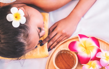 Woman is relaxing on a massage bed with aromatherapy oil and flower top view for Spa and Beauty concept.の写真素材
