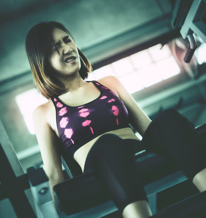 Asian Fitness woman is working out her leg on weight machine in a gym