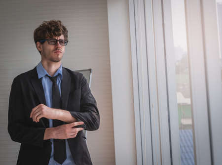 White business with glasses is touching his sleeve getting ready for work.の写真素材
