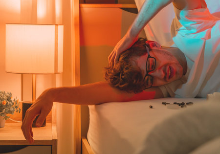 tired caucasian male having stressed problem with sleeping pill medication for insomnia treatment.の写真素材