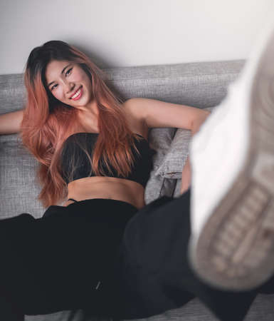 Asian Sporty Fashion model girl is posing with white sneakers shoes on Sofa in an apartment for cool street sport fashionの写真素材