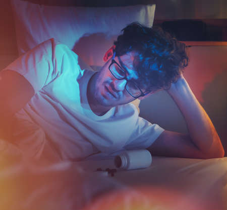 tired caucasian male having stressed problem with sleeping pill medication for insomnia treatment.の写真素材