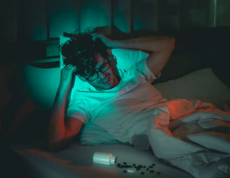 tired caucasian male having stressed problem with sleeping pill medication for insomnia treatment.の写真素材