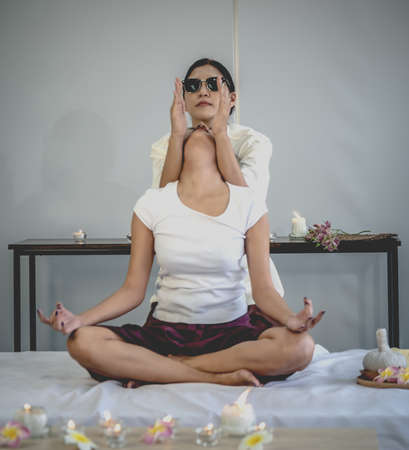Relaxed woman sitting in lotus position and meditating in spa salonの写真素材