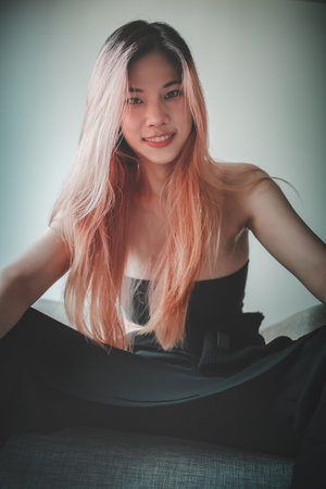 Asian Fashion model girl is posing on Sofa in an apartment for street fashionの写真素材