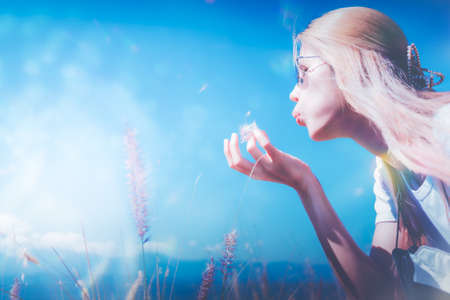 Asian woman is blowing out Grass flower into the wind in nature.の写真素材