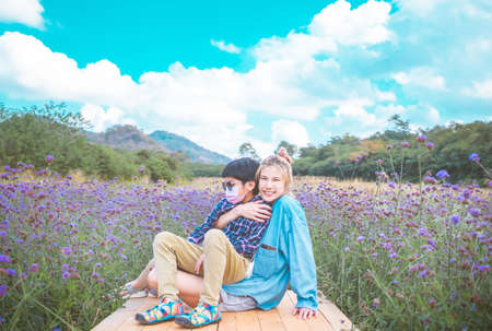 Asian mother is hugging her son in a field full of purple flower.の写真素材