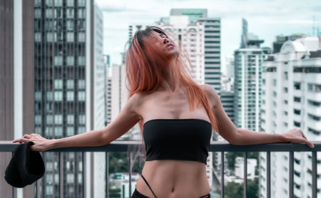 Asian woman with seductive clothing is looking out o Bangkok City from apartment balcony.
