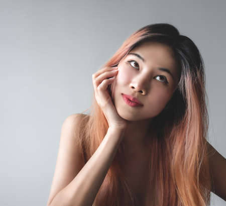 Naked Asian Woman with beauty skin portrait looking happy and playful isolated on gray for fashion and beauty concept.の写真素材