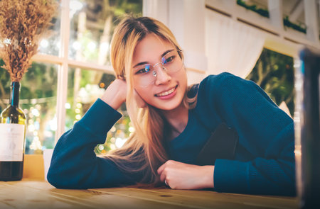 Asian woman with glasses is taking selfire in a night cafe with hapiness and smile,