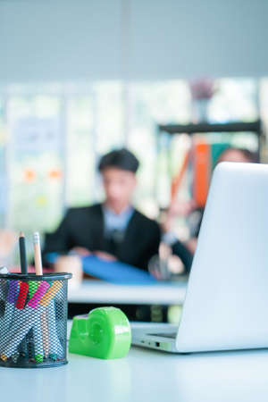 Blurred office workers working in background with office desk and laptop in the front for abstract background.の写真素材