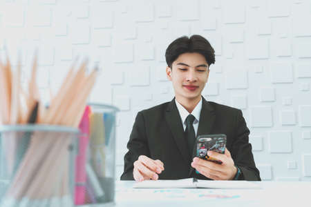 Happy businessman smile while using his mobile phone to check on social media.の写真素材
