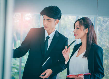 Two Asian Businessman and woman is brainstorming on a glass board for idea and teamwork collaboration concept.の写真素材