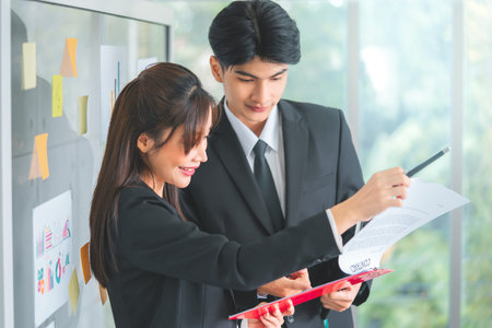 Two Asian Business people, Male and Female is brainstorming and coaching in office meeting.
