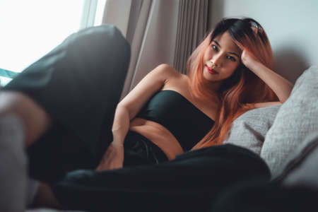 Sporty Asian woman is posing cool on sofa with seductive active black clothing for Street Girl fashion style.の写真素材
