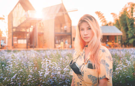 Asian woman portrait freely inside of purple flower field meadow with wooden hut in the background.の写真素材
