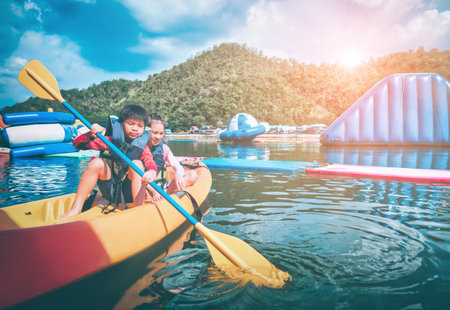 Boy and girl siblings is on a canoe boat in a fun lake for summer activity.