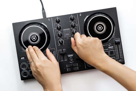 DJ hands is mixing music on DJ Digital mixing controller top view on white background.の写真素材