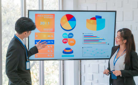 Two Young Thai Business people is presenting financial data on the Visual screen board in business meeting.の写真素材