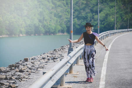 Woman walking on the road side of a Dam in Kanchanaburi, Thailand.の写真素材
