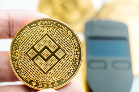 Bangkok, Thailand - 7 August 2022 : a hand holding a Binance Smart Chain Cryptocurrency BNB coin with hardware wallet in background.のeditorial素材