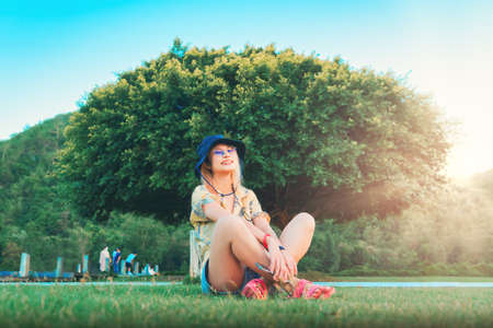 Woman is sitting beside a large tree in a park for, nature and freedom concept..の写真素材