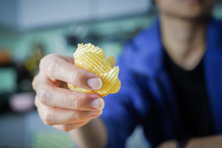 Woman using her hand to pick up potato chips from a bowl, closed up shot.の写真素材