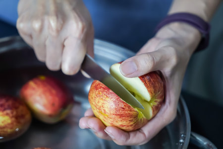 woman hand is cleaning red apple in bucket of water, closed up shotの写真素材