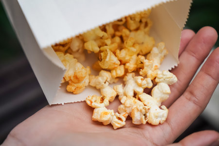 Woman holding popcorn cheese in a paper bag  in the handの写真素材