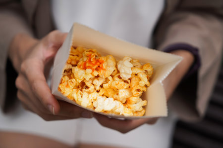 Woman holding popcorn cheese in a paper bag  in the handの写真素材