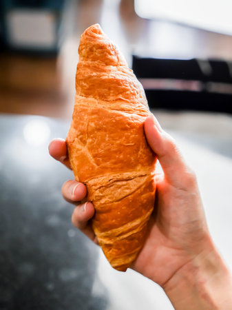 Woman holding a croissant in her hand, closed up shot.の写真素材