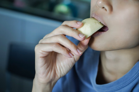 Asian woman is biting on Apple, closed up shot on her mouth eating.の写真素材