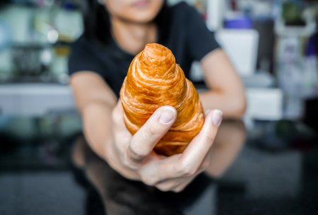 Woman holding a croissant in her hand, closed up shot.の写真素材