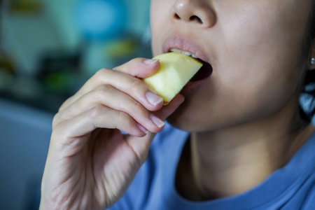 Asian woman is biting on Apple, closed up shot on her mouth eating.の写真素材