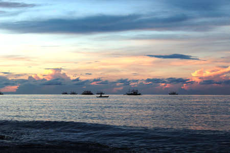 Sunrise on the  beach with fishing boats on the sea.の写真素材