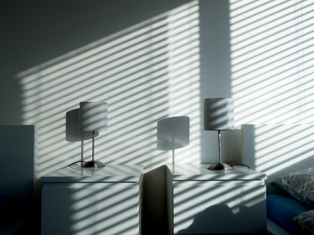 Two lamps on nightables in shadow in a hotel room with falling light