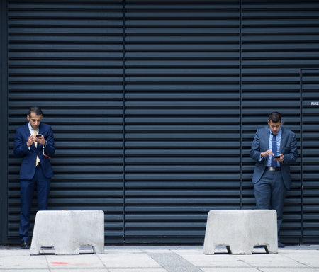 London, NOVEMBER 15: An illustrative photograph of businessmen checking their phones on simple...