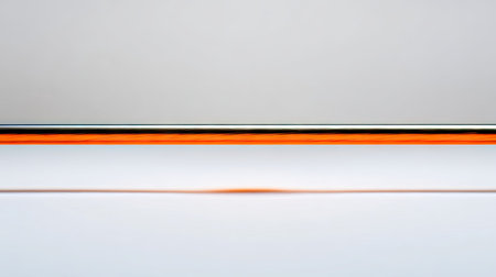 This image presents a minimalist design with a thin orange line positioned between a silver bar and a white backdrop. The composition utilizes clean lines and a smooth surface. The lighting appears soft and diffused, contributing to a sense of simplicity. Suitable for various commercial applications, including web design and print media.の素材