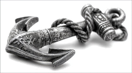 A detailed metal anchor rests on a clean white backdrop, showcasing its intricate design and textures. The composition employs a shallow depth of field, highlighting the central object. The lighting appears soft and diffused, creating subtle shadows. Suitable for various commercial and illustrative applications.の素材
